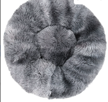 A small dog sleeping curled up inside the fluffy donut pet bed