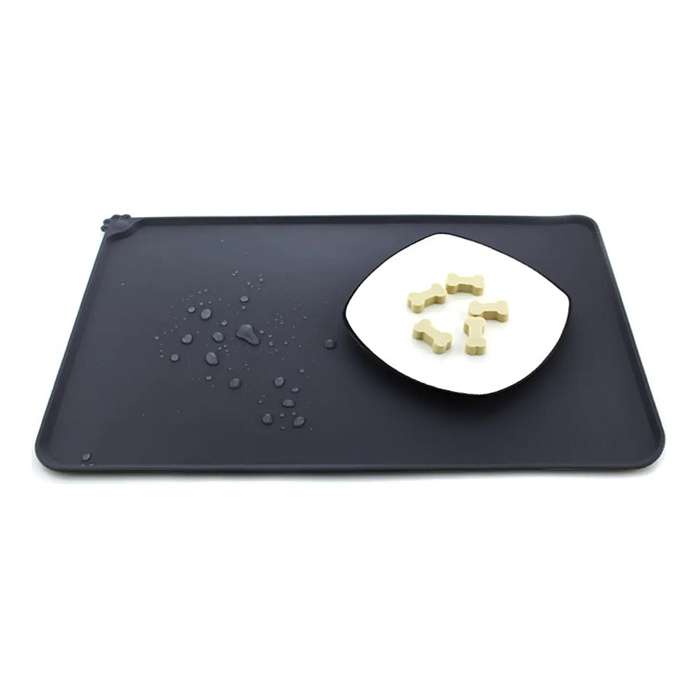 Silicone Pet Feeding Mat — Black mat with raised lip, water beading on the surface and a dish of treats